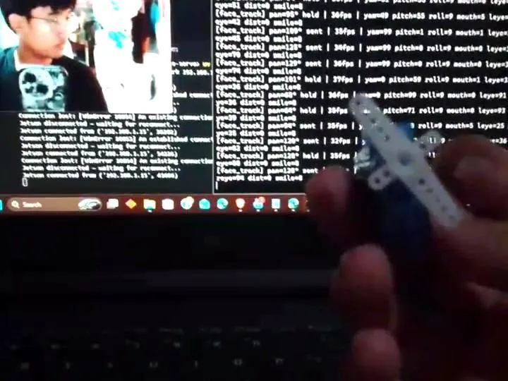 Debugging the face tracker: a servo in hand in front of a laptop running the tracking code