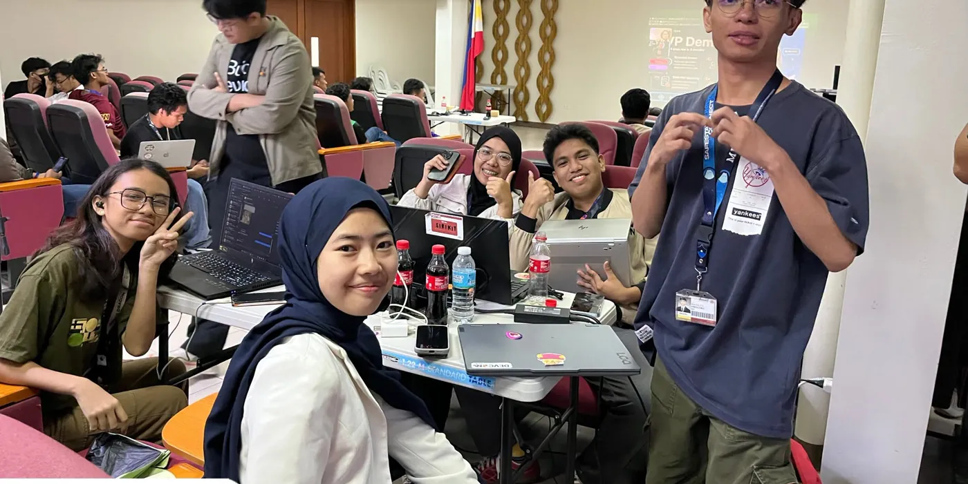 A smiling hackathon team with laptops, giving thumbs up in Iligan