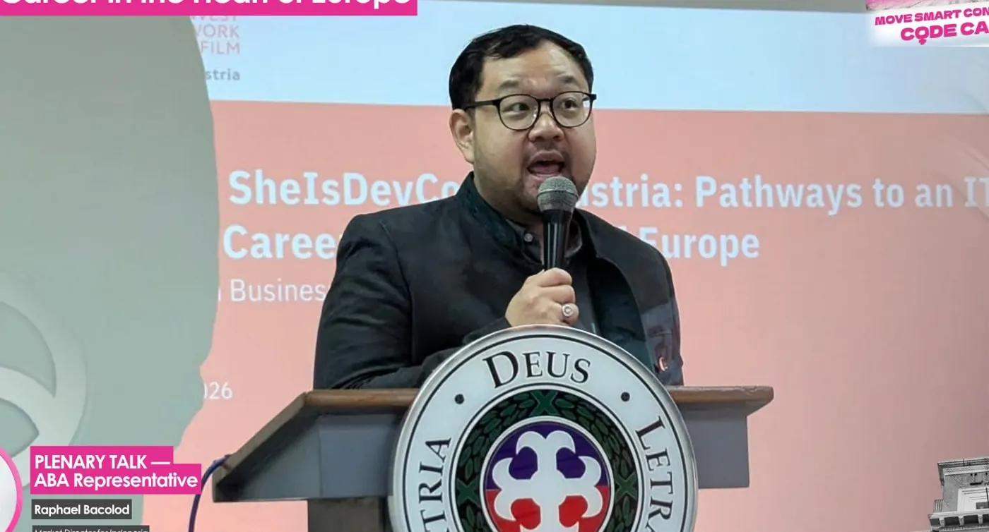Raphael Bacolod giving the plenary talk From SheIsDevCon to Austria at a Letran podium