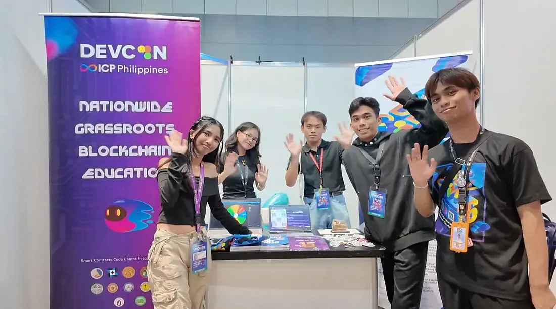 Interns waving at a DEVCON blockchain education booth