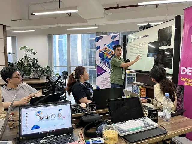 An intern teaching a session on coding with an AI assistant at a whiteboard screen