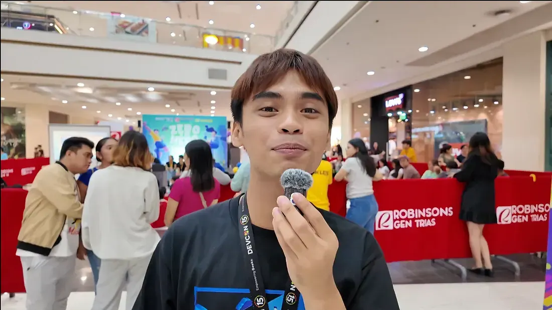 An intern speaking into a microphone at a community event in a mall