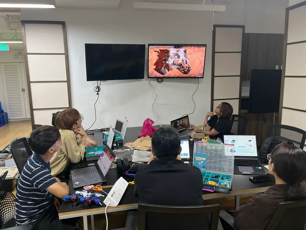 Interns with robotics kits watching a Mars rover video during a build session